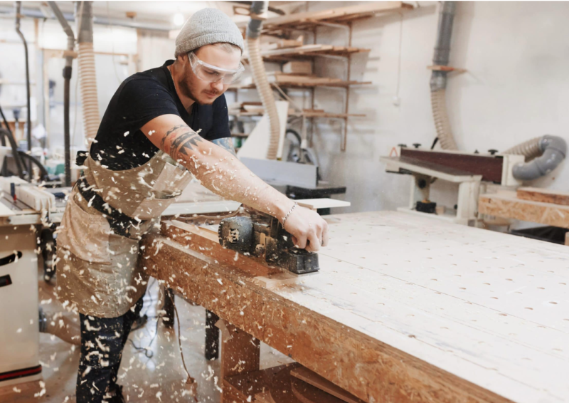 Woodworker using hand plane on wooden surface