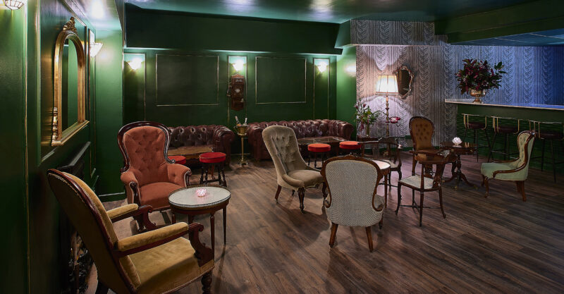 Elegant lounge with green walls and vintage furniture