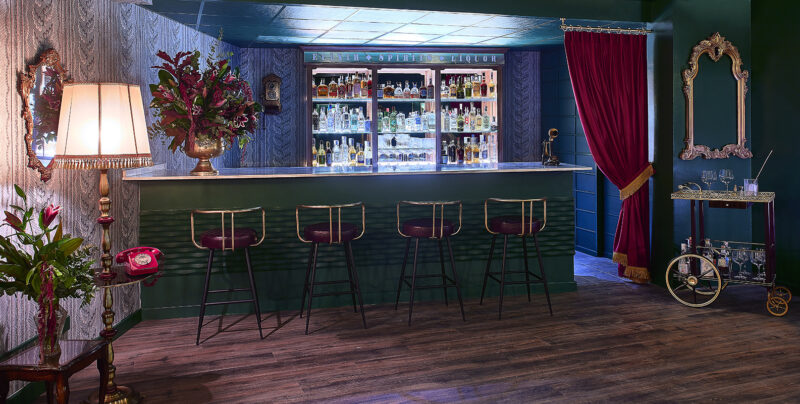 Upscale bar interior with green counter and brass stools