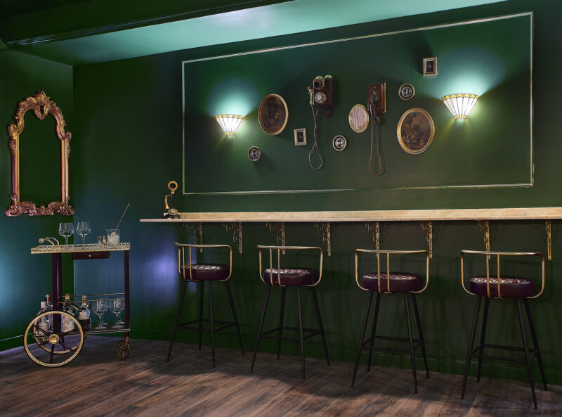 Elegant green bar interior with vintage decor and bar seating
