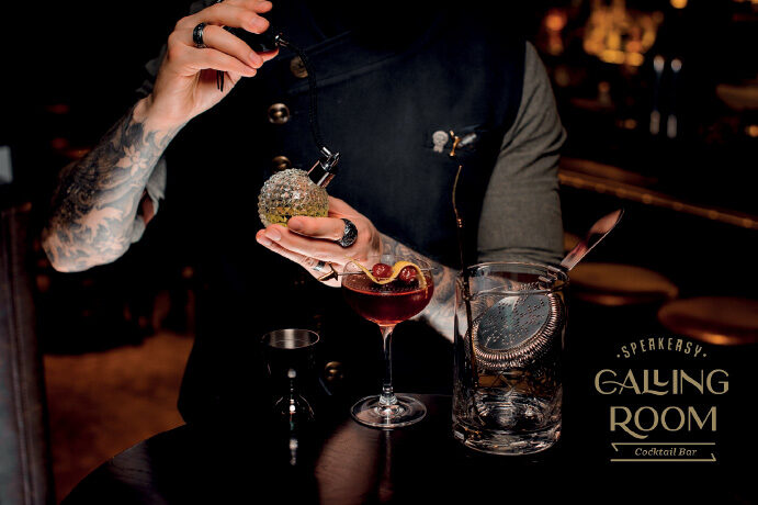 Bartender crafting cocktail with gold garnish at upscale bar