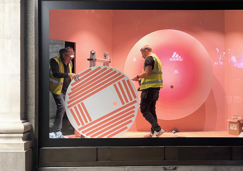 Two workers installing display in retail window